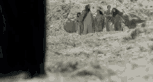 a black and white photo of a group of people standing in a pile of dirt .