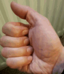 a close up of a person 's hand giving a thumbs up gesture