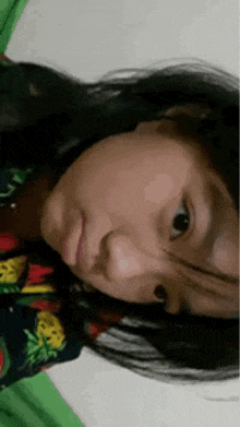 a young girl is laying on a bed with a pineapple shirt on .