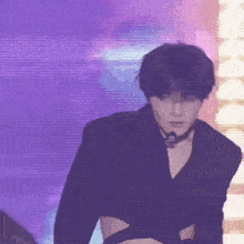 a man is standing on a stage wearing a black crop top and a choker .