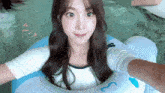 a young woman is sitting on a blue raft in the water .