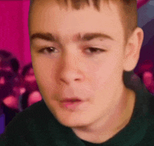 a close up of a young man 's face with a pink background .