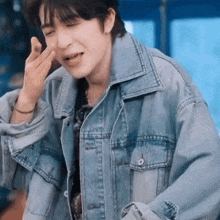 a man wearing a denim jacket is making a face