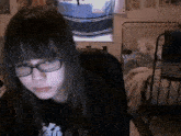 a girl wearing glasses is sitting in a chair in a bedroom