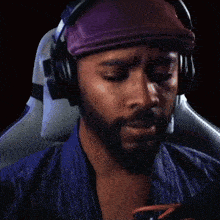 a man with a beard wearing headphones and a bandana