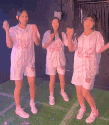 three young girls are standing next to each other on a stage .