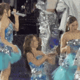 a woman in a blue dress holds a microphone