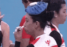 a woman wearing a blue ice pack on her head is eating a sandwich .