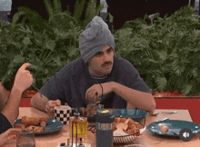 a man with a towel wrapped around his head sits at a table with plates of food