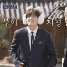 a man in a suit and tie is wearing bunny ears and ear muffs .