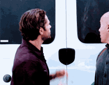 two men are standing in front of a white van and talking