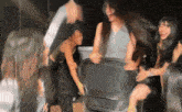 a group of women are laughing and playing with a chair