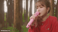 a woman in a red sweater is singing into a pink microphone .