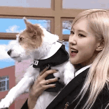 a woman is holding a dog wearing a black collar .