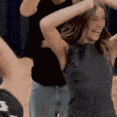 a woman in a black top is dancing with a man in a black shirt behind her .