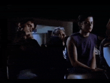 a man in a purple shirt is standing in a dark room