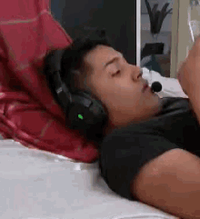 a man is laying on a bed wearing headphones and a headset .