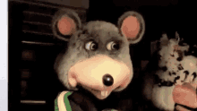 a person in a chuck e cheese mouse costume is holding a stuffed animal .