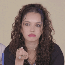 a woman with curly hair and a necklace with the letter d