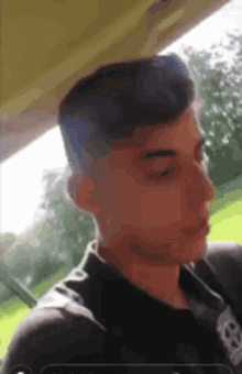 a young man with a shaved head is sitting in a car looking out the window .