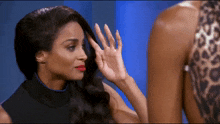 a woman is touching her hair while another woman looks on