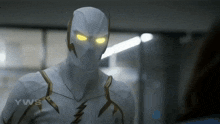 a close up of a person wearing a white and gold superhero suit with yellow eyes