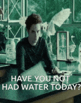 a man sitting at a desk with the words " have you not had water today " on the screen