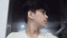 a young man in a white t-shirt looks at the camera