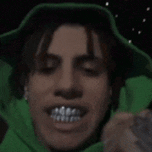 a close up of a person 's face with their mouth open and a green jacket on .