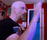 a bald man in a black shirt is standing in front of a door