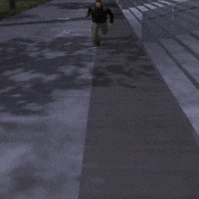 a man standing on a sidewalk wearing a black jacket and green pants