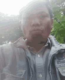 a man wearing a jacket and a blue shirt is taking a selfie with his eyes closed .