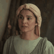 a woman with a turban on her head looks at the camera with a serious look on her face