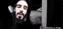 a man with long hair and a beard is peeking out from behind a door