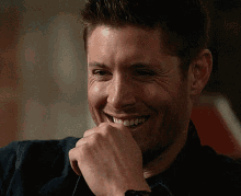 a close up of a man laughing with his hand on his face