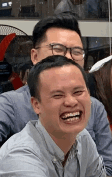 a man wearing glasses is laughing with another man .