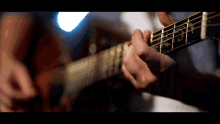 a close up of a person playing an acoustic guitar with the letter n on the neck