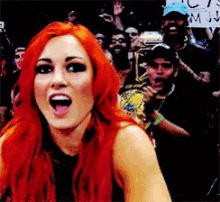 a woman with red hair stands in front of a crowd holding a sign that says ' i 'm ' on it