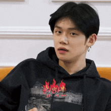 a young man wearing a black hoodie with flames on the front