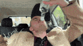 a man in a scarecrow costume is drinking from a bottle while sitting in a car .