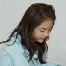 a woman with long hair is wearing a blue jacket and looking down