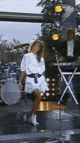 a woman in a white dress is dancing on a stage in front of a keyboard