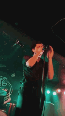 a man singing into a microphone in front of a sign that says ' ts ' on it
