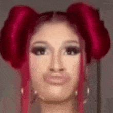 a close up of a woman 's face with red hair in two buns .