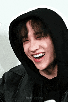 a close up of a man wearing a black hoodie and smiling .