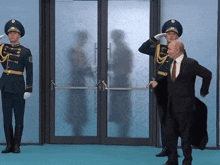 a man in a suit stands in front of two soldiers who salute