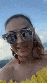 a woman wearing sunglasses and earrings is smiling and looking at the camera