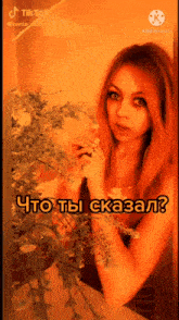 a woman is standing in front of a plant with the words " что ты сказал " on the bottom