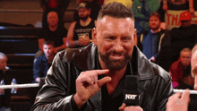 a man with a beard is talking into a microphone that says nxt on it