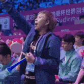 a woman in a blue jacket with the word sudirma on the back